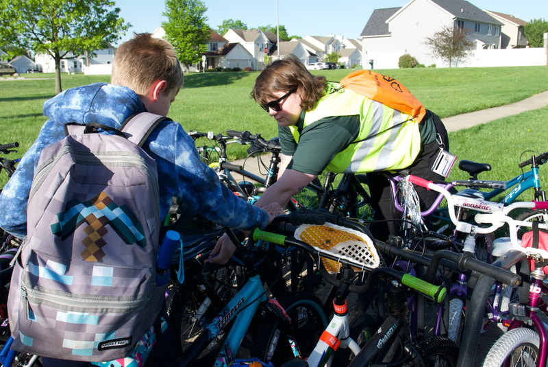 A C-U SRTS volunteer helping a student lock their bike at a busy bike rack.