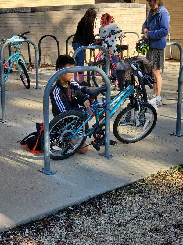 A student locks their bike on a bike rack.